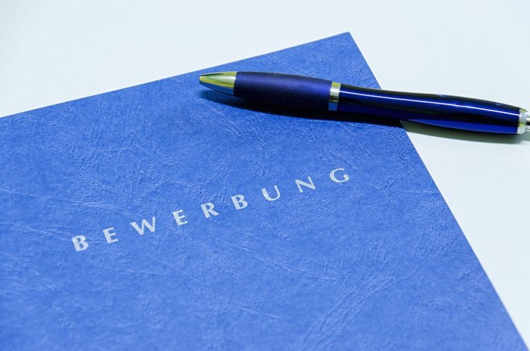 Bild einer blauen Bewerbungsmappe mit einem Stift, der darauf liegt
