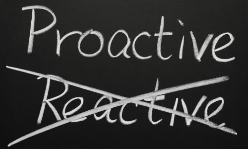 Crossing out reactive and writing proactive on a blackboard.